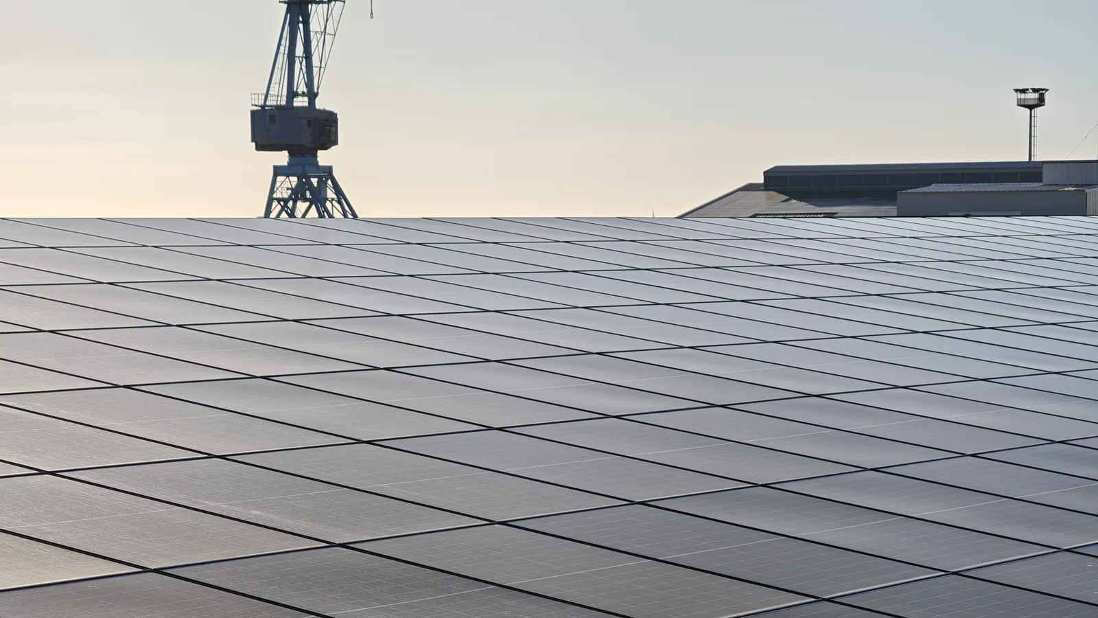 Centrale photovoltaïque de grande surface en toiture industrielle, au lever du jour